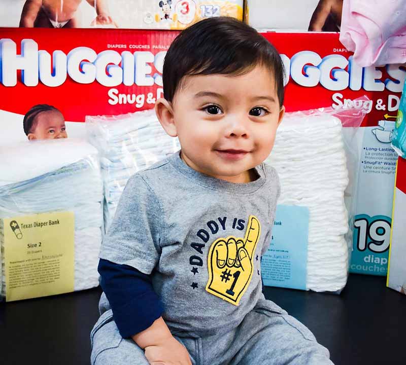 Baby in front of pile of diapers